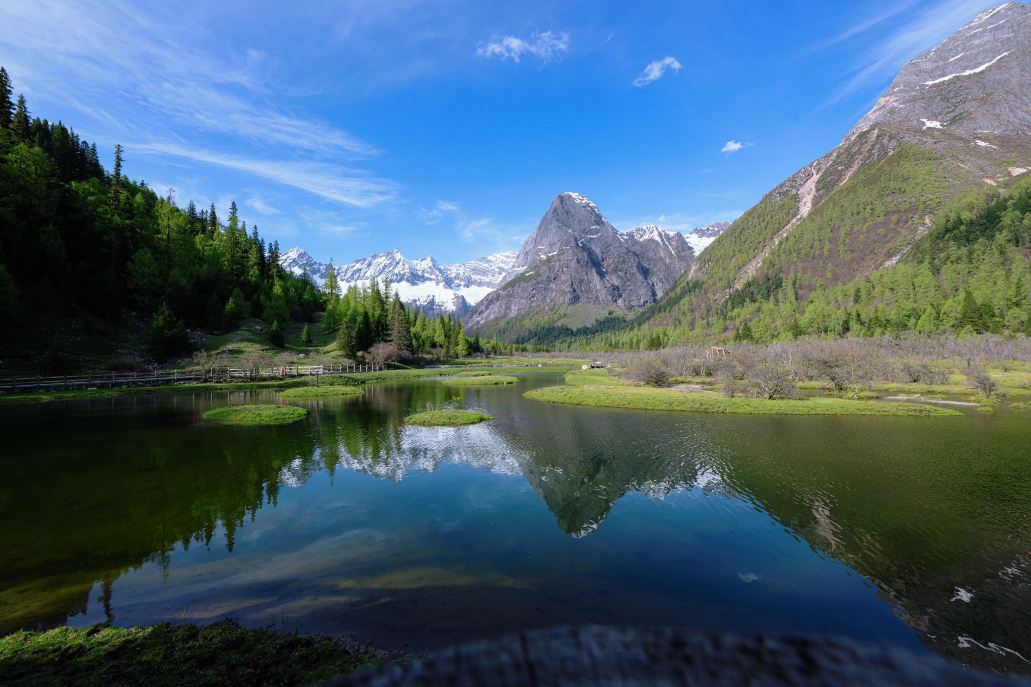 Alpine lake and grassland under a vast blue sky