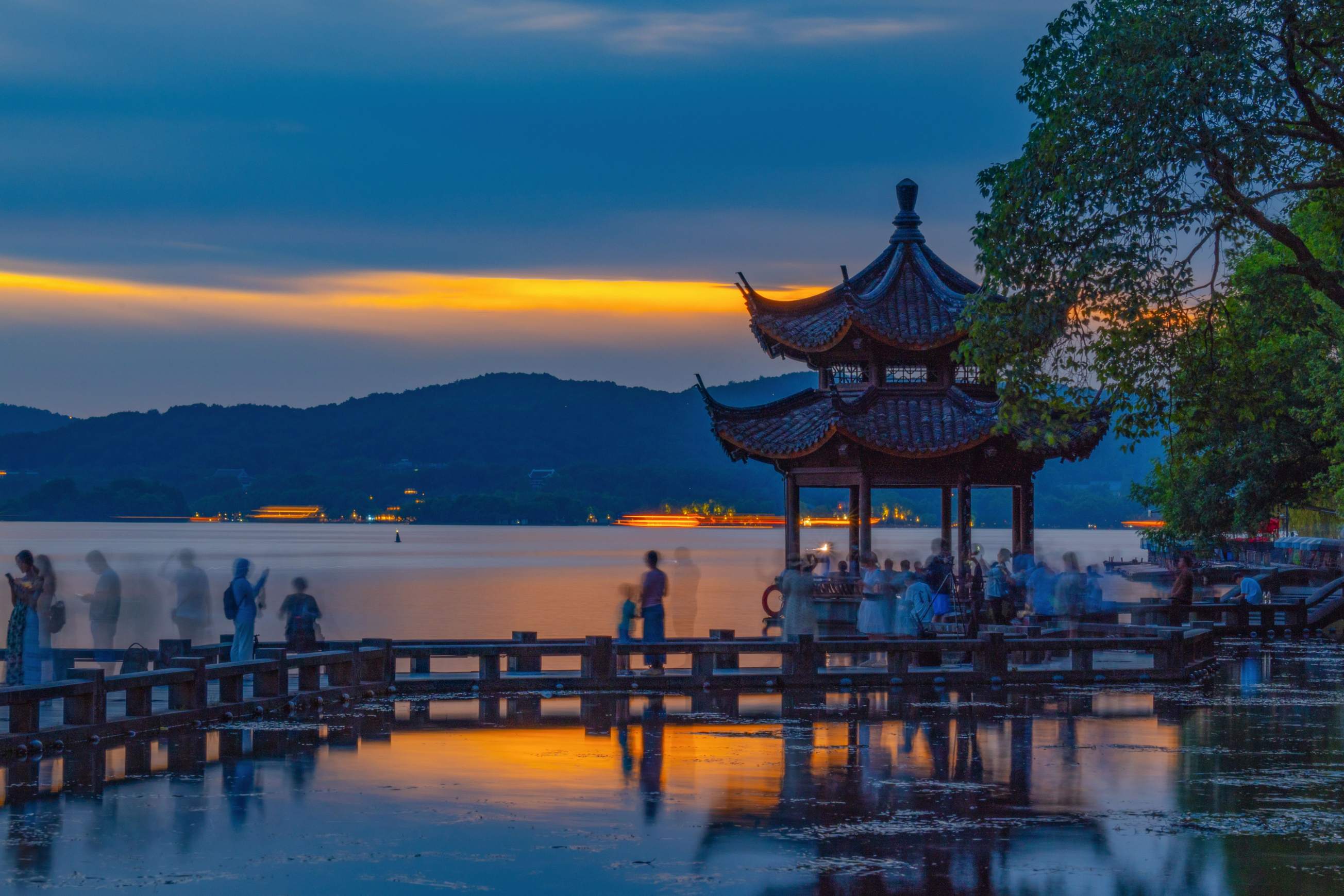 West Lake at sunset with pagoda and mountains in Hangzhou, China